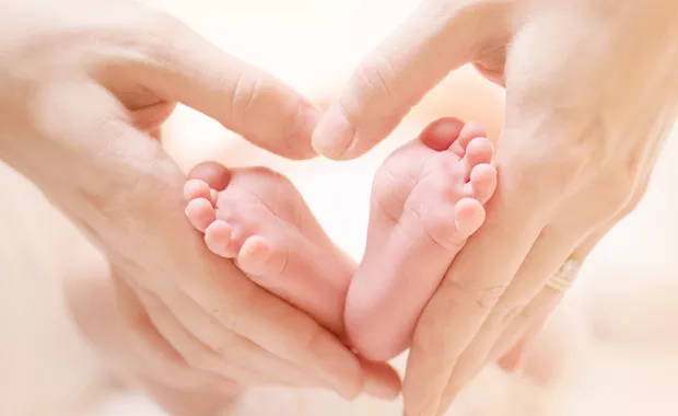 赤ちゃんの足を抱く親の手